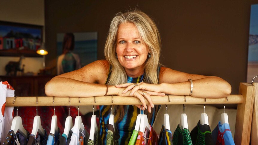 Mother of five, Vivien Mitchell, standing in front of a rack of clothing she has designed.