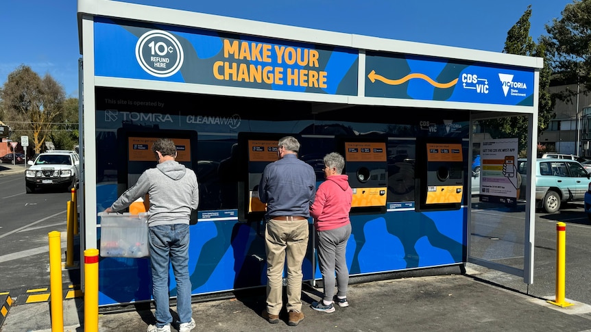 People stand at a container deposit station.