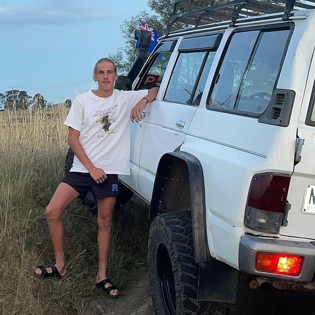 Jason Langhans wearing a white t-shirt and leaning against a white 4WD in an undated photograph.