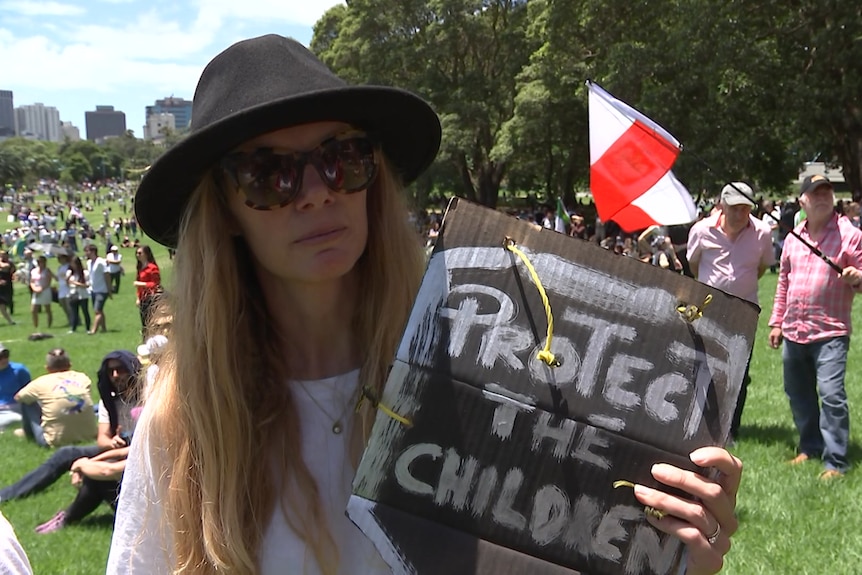 A woman holding a sign saying 'protect the children'.