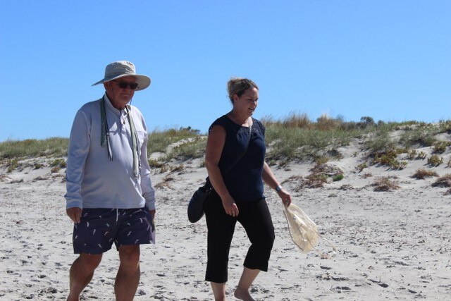 George Brown and Dr Linda Davies walking on a beach.