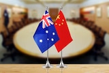 Australian and Chinese flags in the foreground with a board room table in the background.