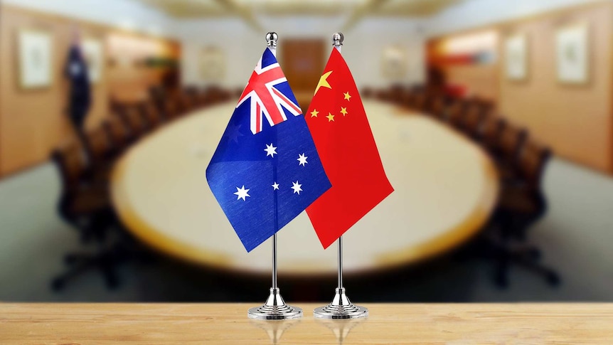前景是澳大利亚和中国的国旗，背景是会议室的桌子。