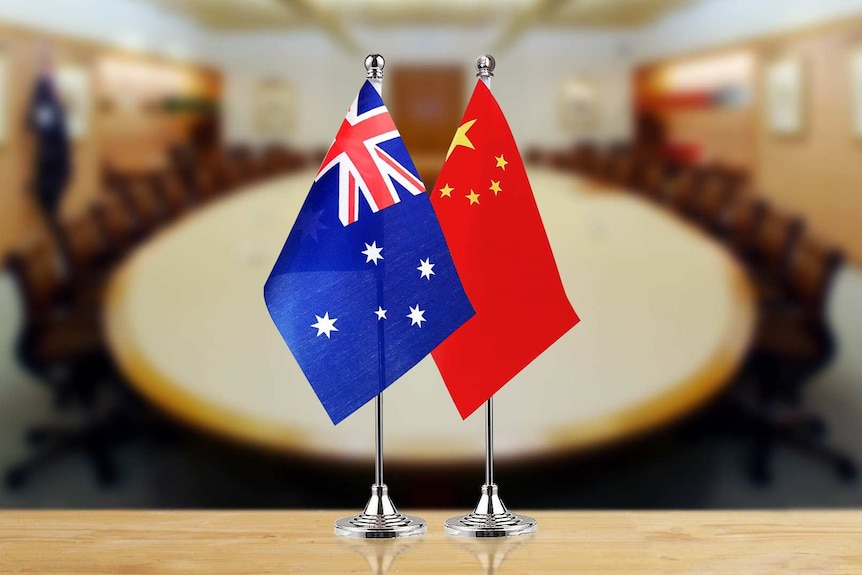 前景是澳大利亚和中国的国旗，背景是会议室的桌子。