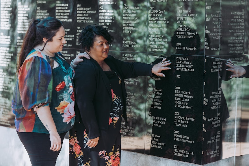 Two women looking at a memorial wall for miners.  