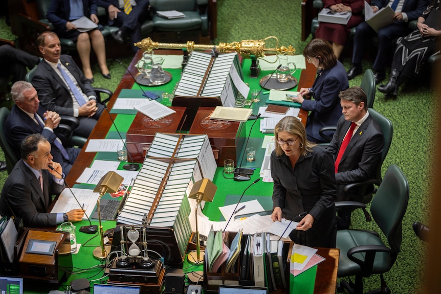 Jacinta Allan standing at a desk surrounded by other politicians. 