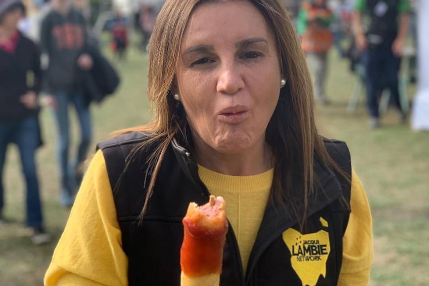 With a fair in the background, Jacqui Lambie eats a sauce-covered sausage