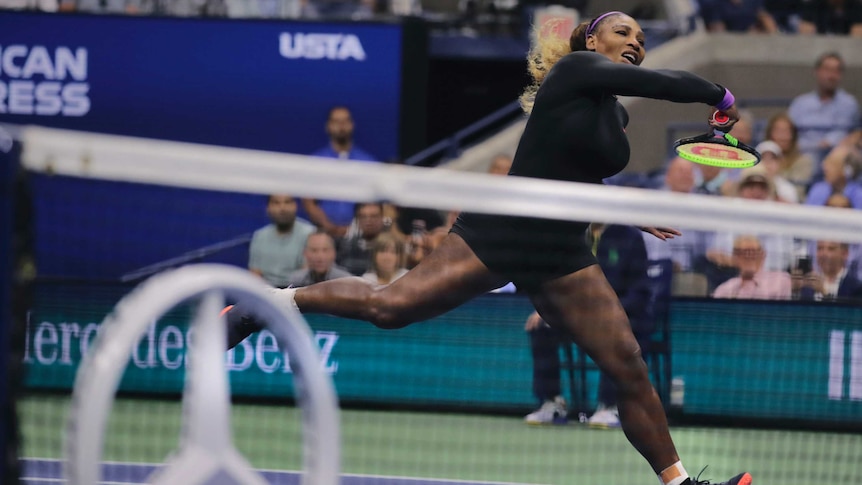 A tennis player in full stride completes her follow-through after hitting the ball over the net.