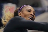 A tennis player in full stride completes her follow-through after hitting the ball over the net.