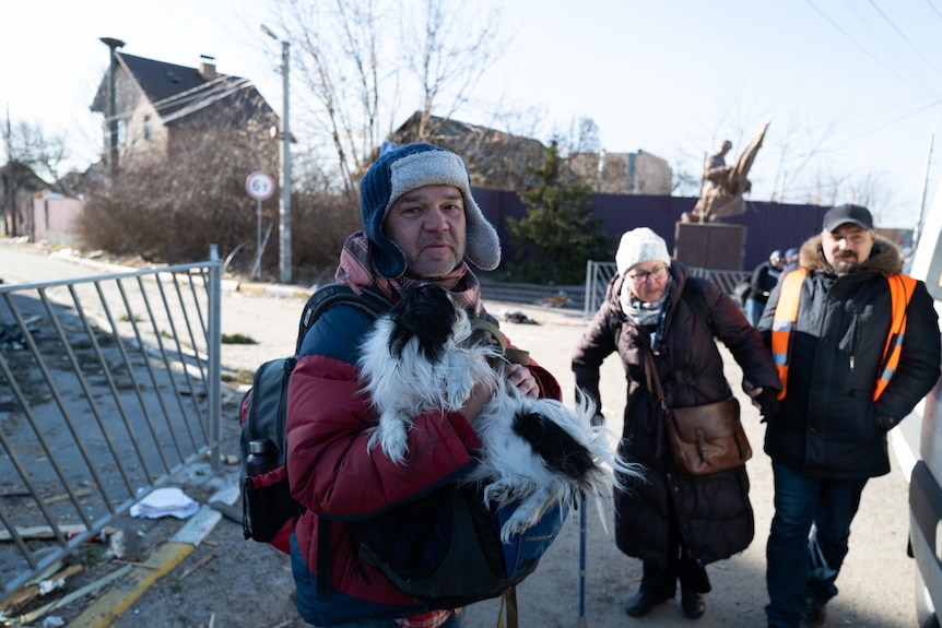 A middle aged man holding a small dog in Irpin.