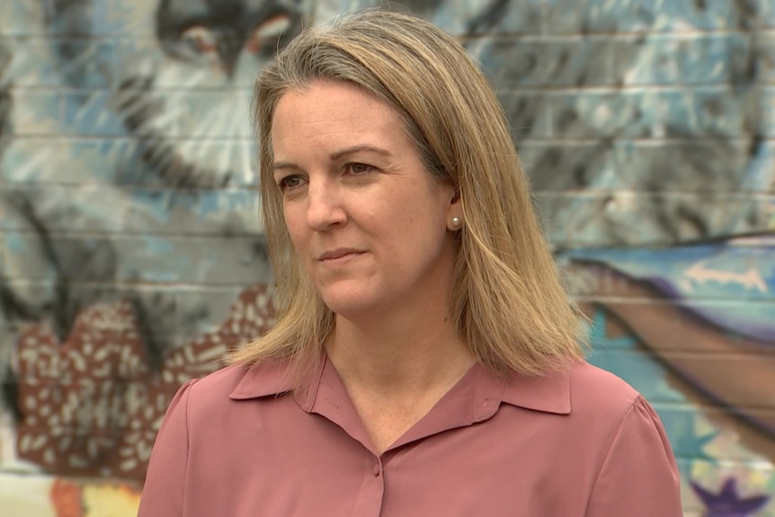 A woman with blonde hair looks serious.