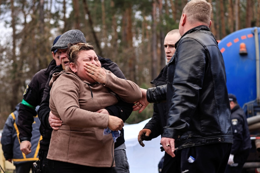 A mother reacts in sadness as police talk to her.