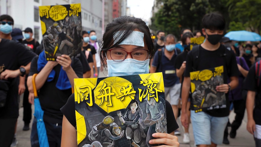 A woman holds a poster showing protesters and medical workers with the words "together".