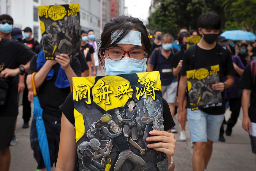 A woman holds a poster showing protesters and medical workers with the words "together".