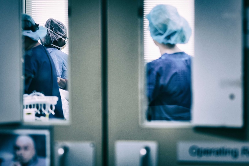 Looking through a set of doors where three people in medical scrubs can be seen