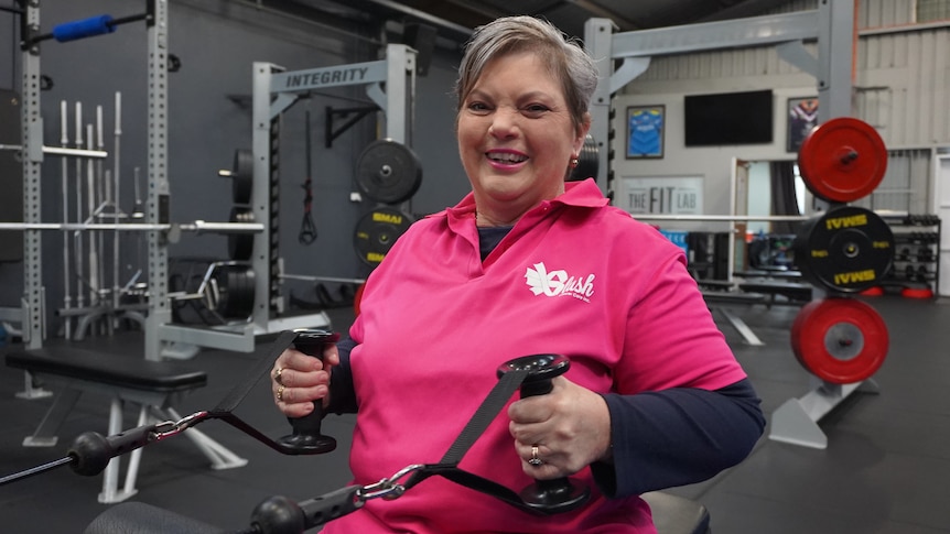 A woman wearing pink pulling gym equipment