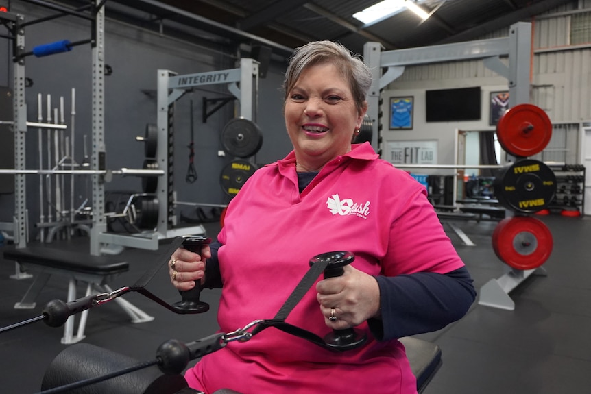 A woman wearing pink pulling gym equipment