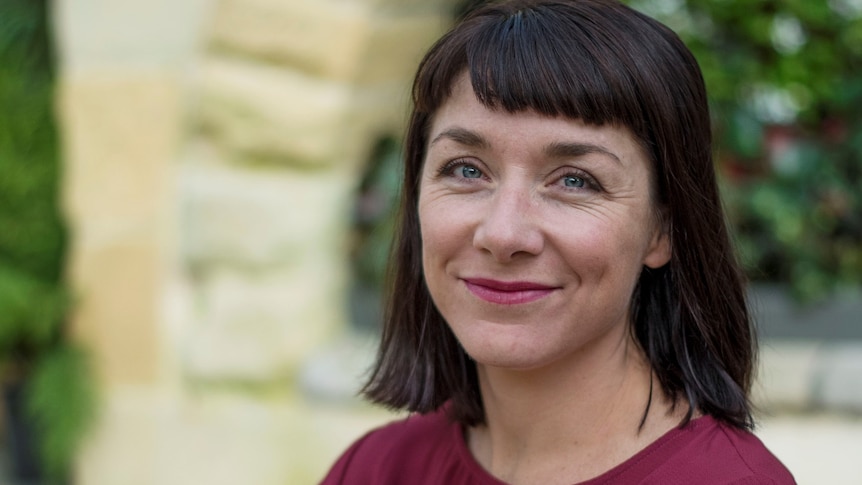 A woman with dark hair and a maroon shirt smiles for a story on common misconceptions about ADHD.