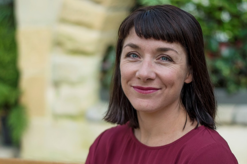 A woman with dark hair and a maroon shirt smiles for a story on common misconceptions about ADHD.