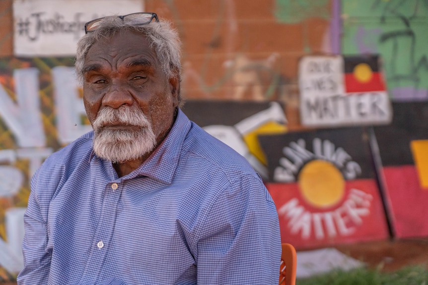 An elderly Indigenous man looks at the camera
