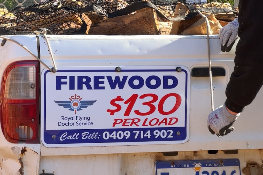 A ute with a sign on the back advertising the price of the wood
