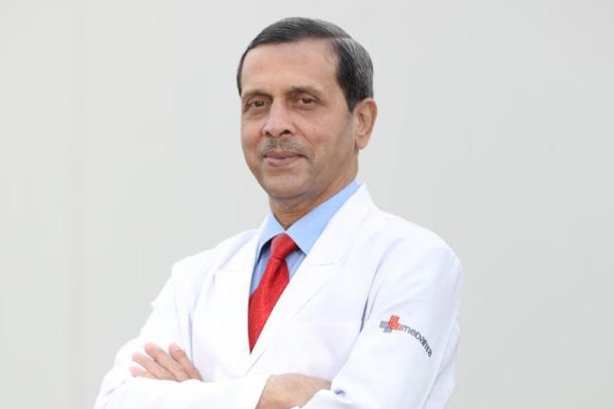 Le professeur Arvind Kumar se tient les bras croisés dans une blouse blanche de médecin. 