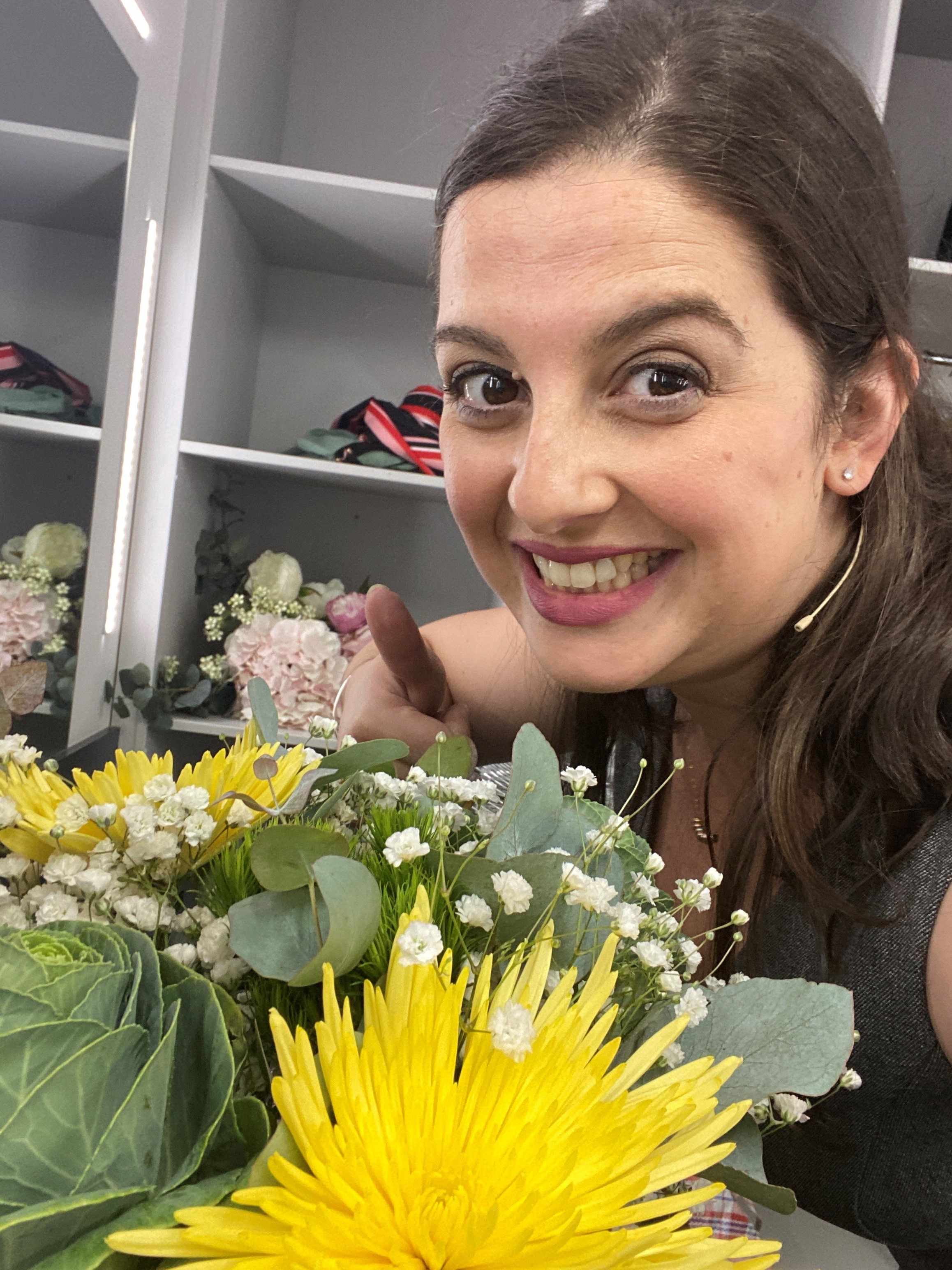 A woman in makeup holds a bunch of flowers