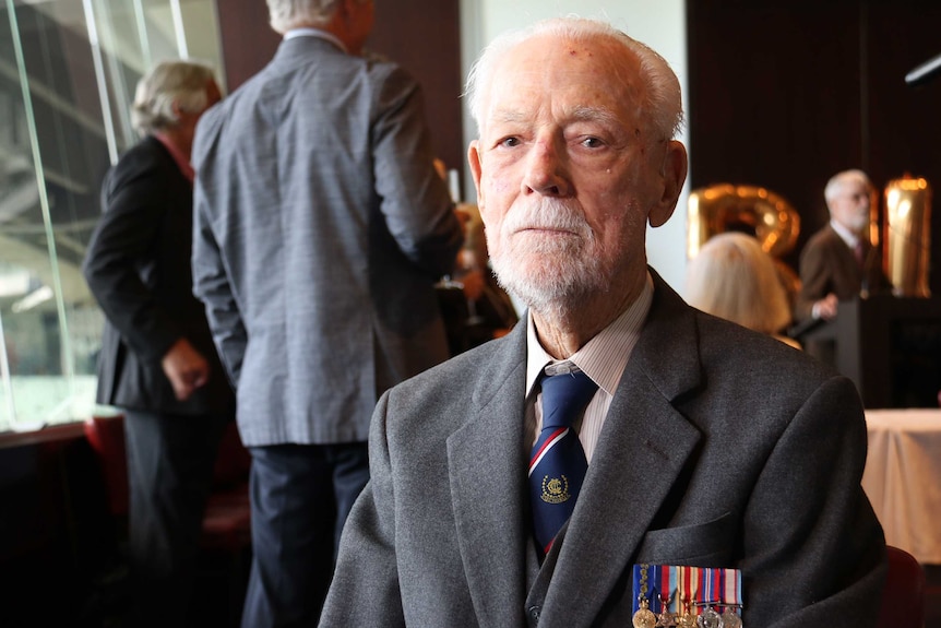 Close-up of WWII veteran Bill Rudd, who is wearing a tie and his war medals.