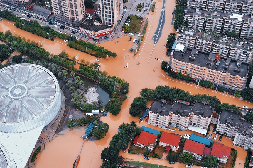 A view from above shows buildings and streets surrounded by floodwater.