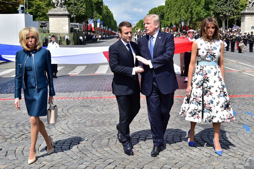 Emmanuel Macron and Donald Trump walk, talk and shake hands while Brigitte Macron and Melania Trump walk on the sides in Paris.