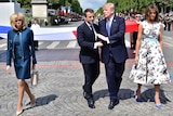Emmanuel Macron and Donald Trump walk, talk and shake hands while Brigitte Macron and Melania Trump walk on the sides in Paris.