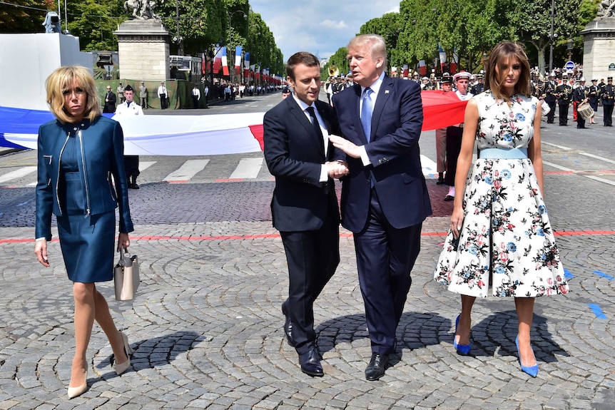 Emmanuel Macron and Donald Trump walk, talk and shake hands while Brigitte Macron and Melania Trump walk on the sides in Paris.