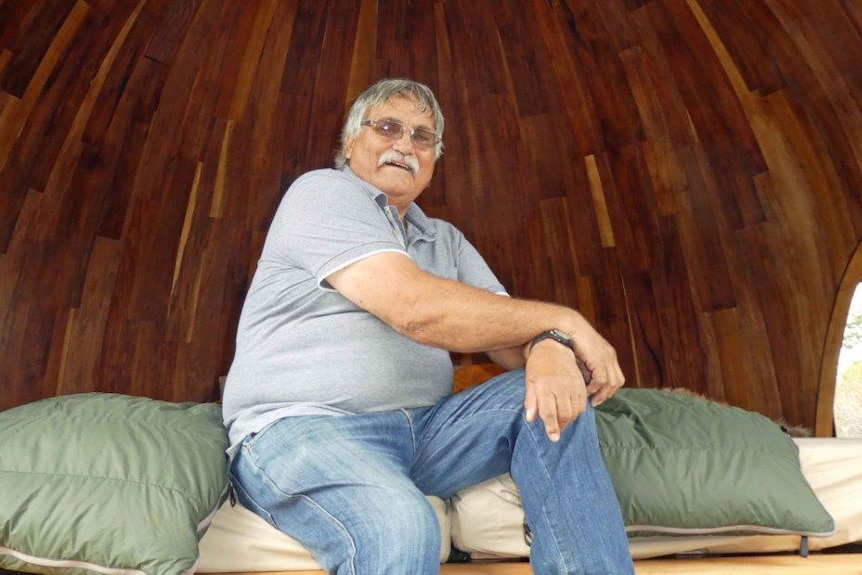 Clyde Mansell sits in a sleeping hut