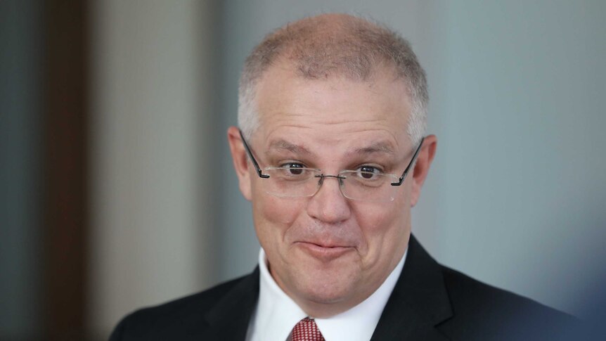 Scott Morrison, with pursed lips and raised eyebrows, wearing glasses and a dark suit.