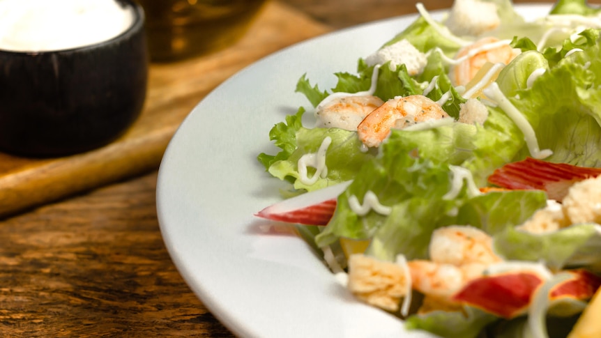 A vibrant prawn and lettuce and radish salad in a bowl.