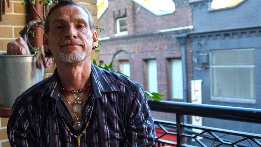 'Psychic wizard' Marque Caban sitting on balcony wearing stone jewellery.