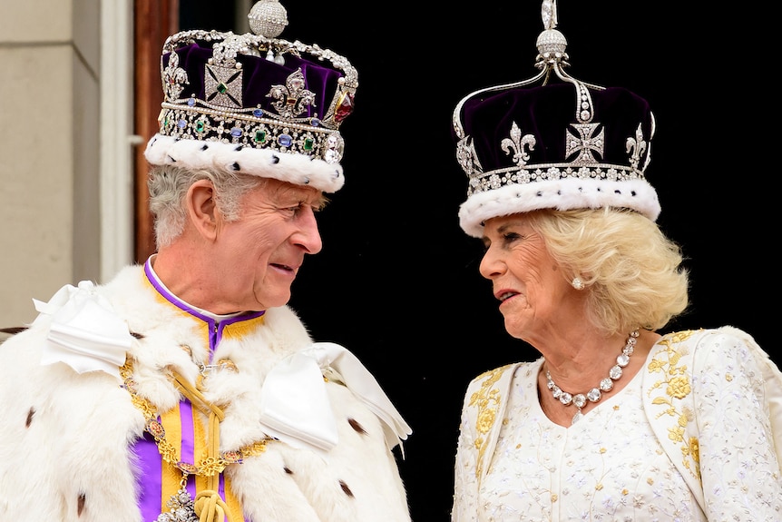 King Charles III and Queen Camilla talk while on the royal balcony.