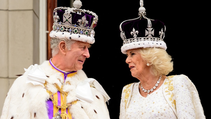 King Charles III and Queen Camilla talk while on the royal balcony.