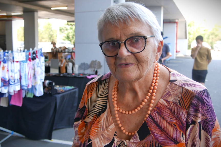 Woman with glasses and coral coloured necklace.