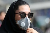 A woman wears a black medical mask.