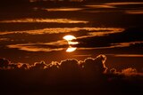 A partial solar eclipse rises behind clouds in Arbutus.