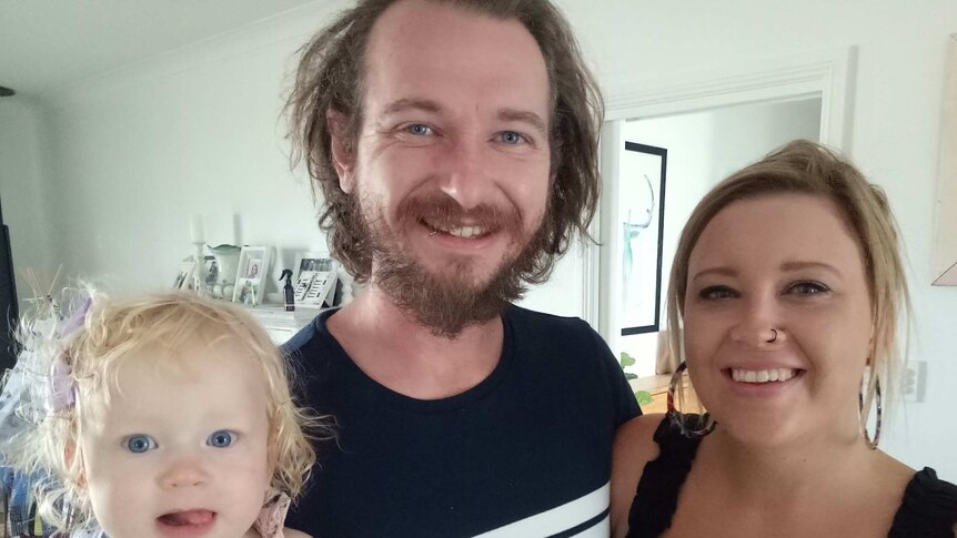 Michael Muchow and Melody Moko pose with their toddler daughter