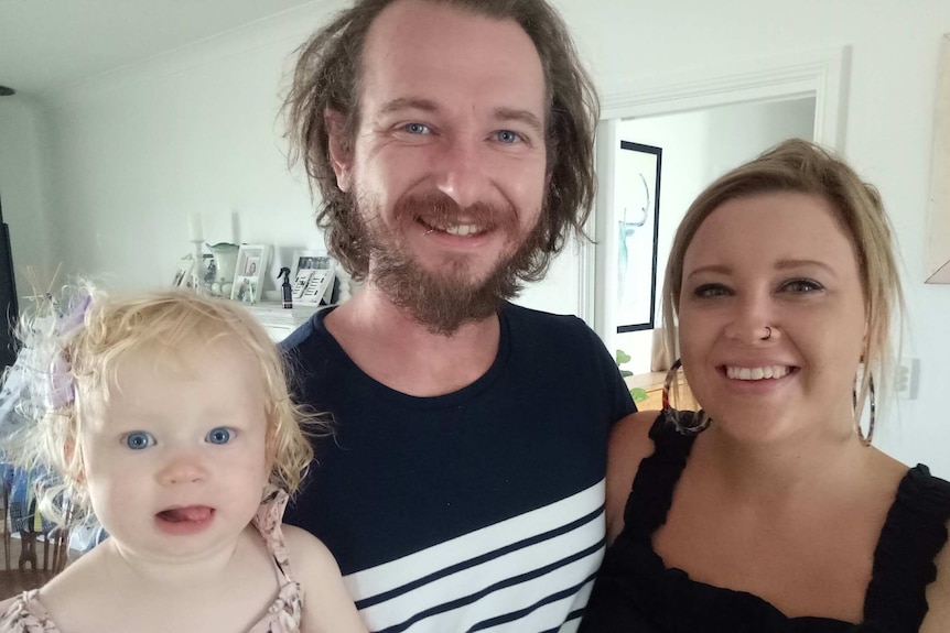 Michael Muchow and Melody Moko pose with their toddler daughter