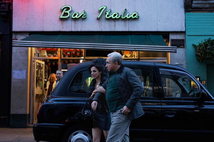 Amy, left, holds onto her dad Mitch's hand as they pass in front of his black cab in front of Bar Italia.