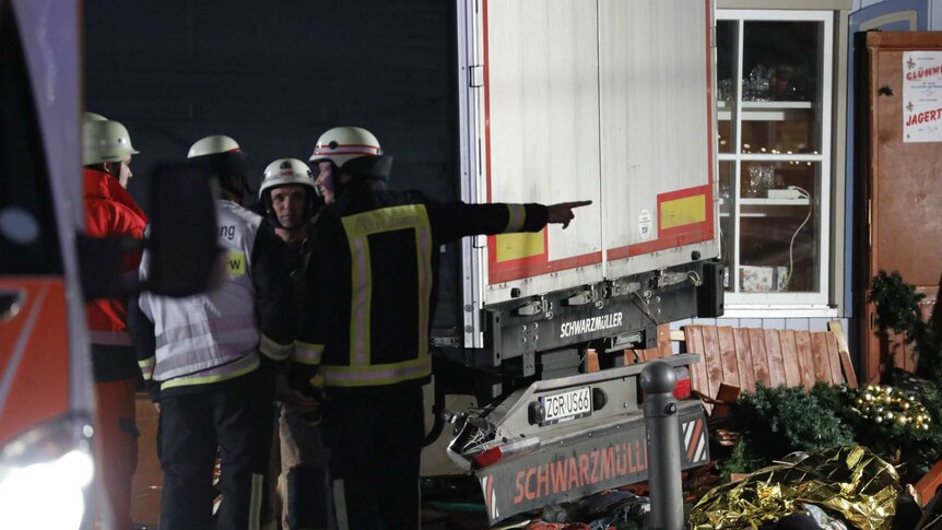 Firefighters stand next to the truck and market debris in Berlin.