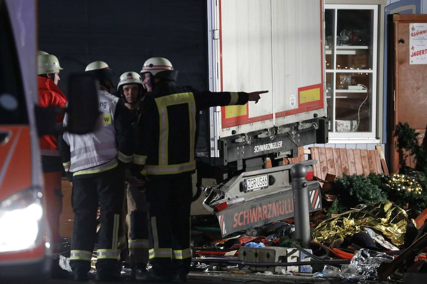 Firefighters stand next to the truck and market debris in Berlin.