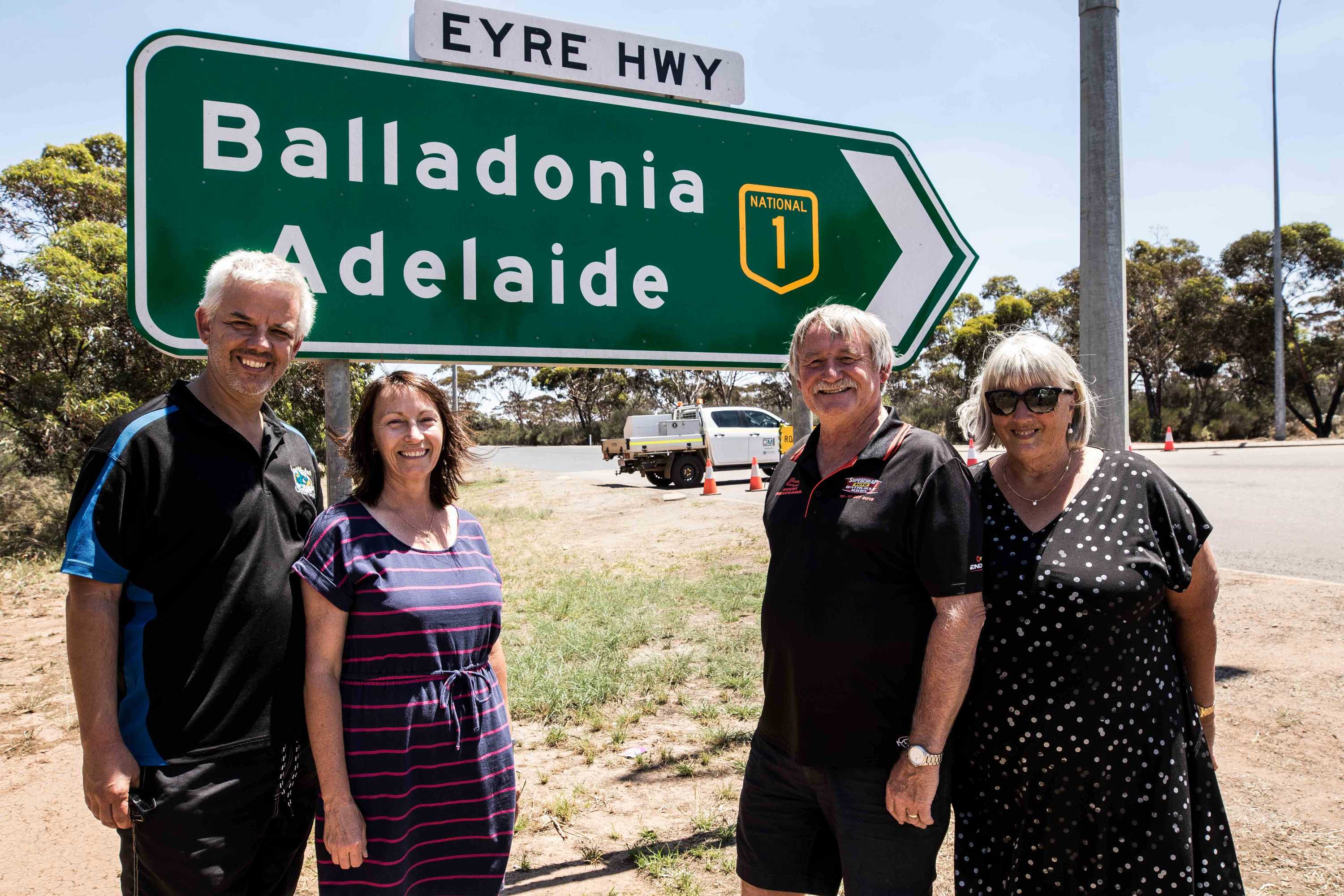 Four people standing next to a road closure sign