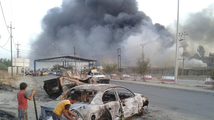 Burnt car in Iraq city of Mosul after attacks