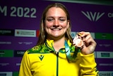 swimmer chelsea hodges smiles while holding up her commonwealth games bronze medal