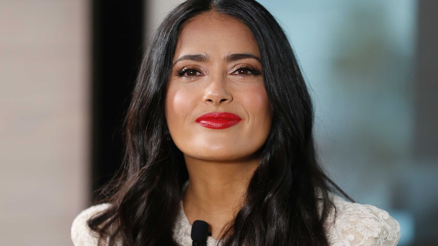 Salma Hayek at a photocall wearing a white lacedress and red lipstick in cannes